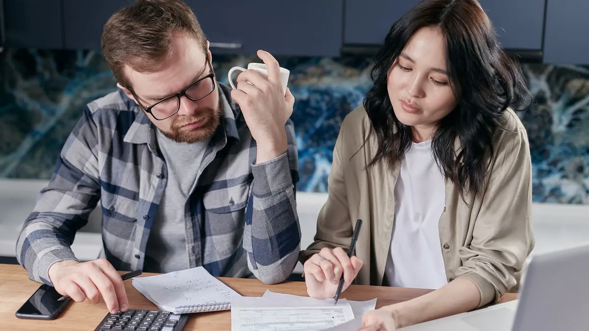 Couple examinant ses factures et ses charges de copropriété avec une calculatrice